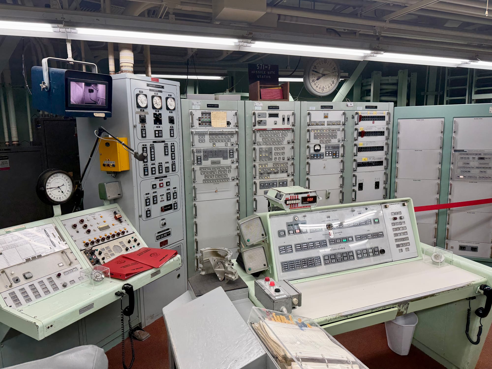A photo of the view from the left side of the control room. The same desk and cabinets are visible, and a few additional devices, like a radio panel, are visible