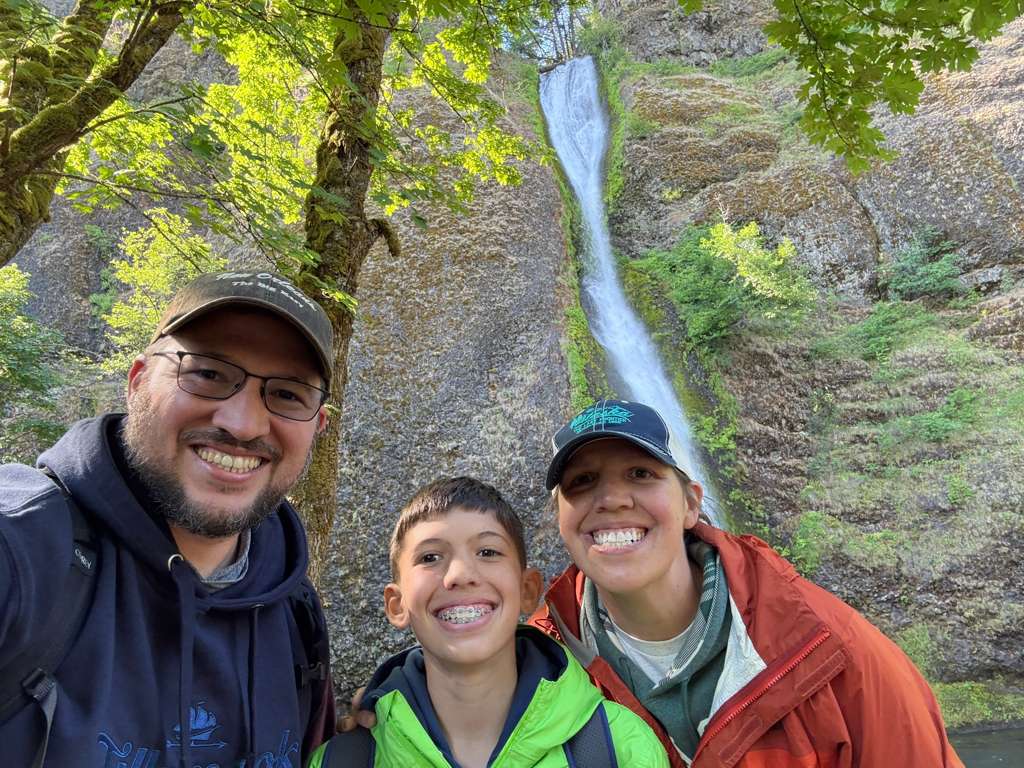 A picture of Jared Harley with his wife and son in front of a waterfall.